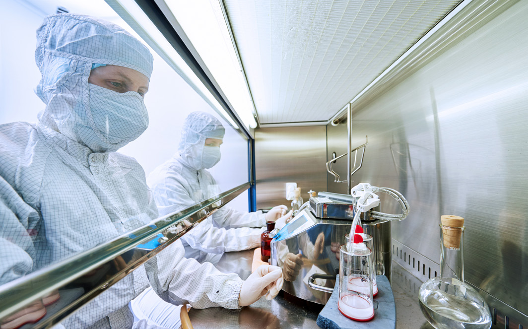 Gowned operator performing sterility testing in a laminar air flow hood