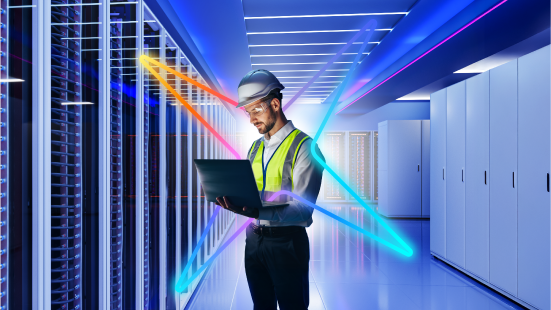 employee with PPE on looking at laptop in data center