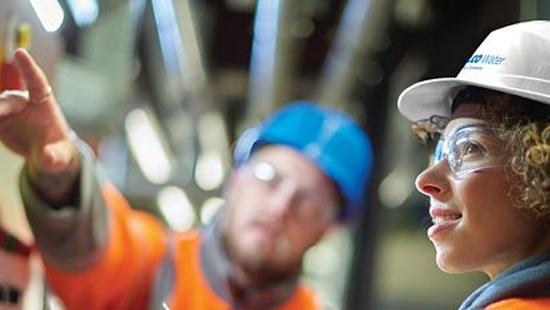 Employees in a plant reviewing a controler