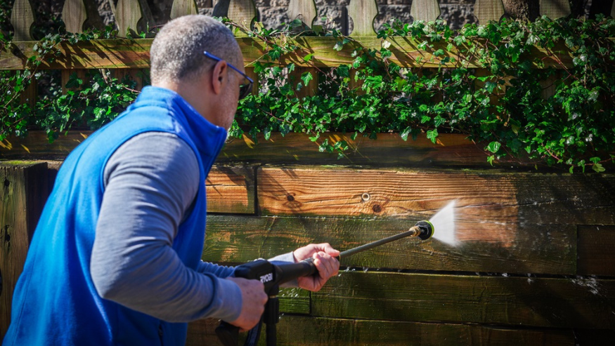 A man cleaning a fence with Ecolab product Wood Deck and Fence Pressure Wash Concentrate Outdoor Cleaner 